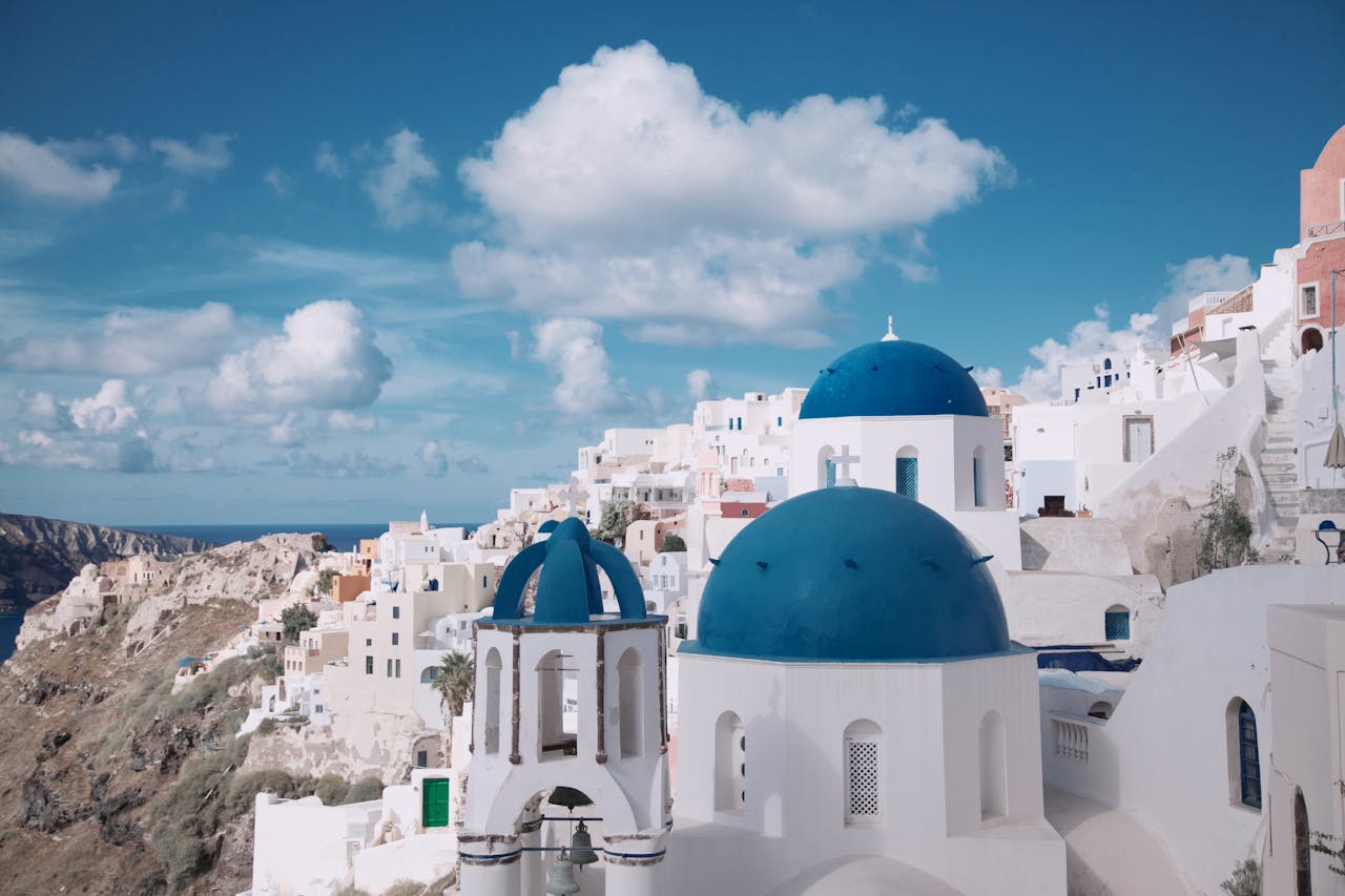 Services Breathtaking view of Oia's iconic blue-domed churches against a vibrant sky in Santorini, Greece.