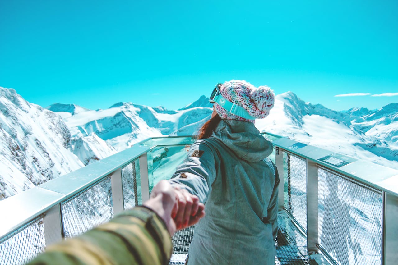 Mastering the First Impression: Your intriguing post title goes here A woman in winter clothing holds a hand and walks on a scenic snow-covered mountain deck in Zell am See.